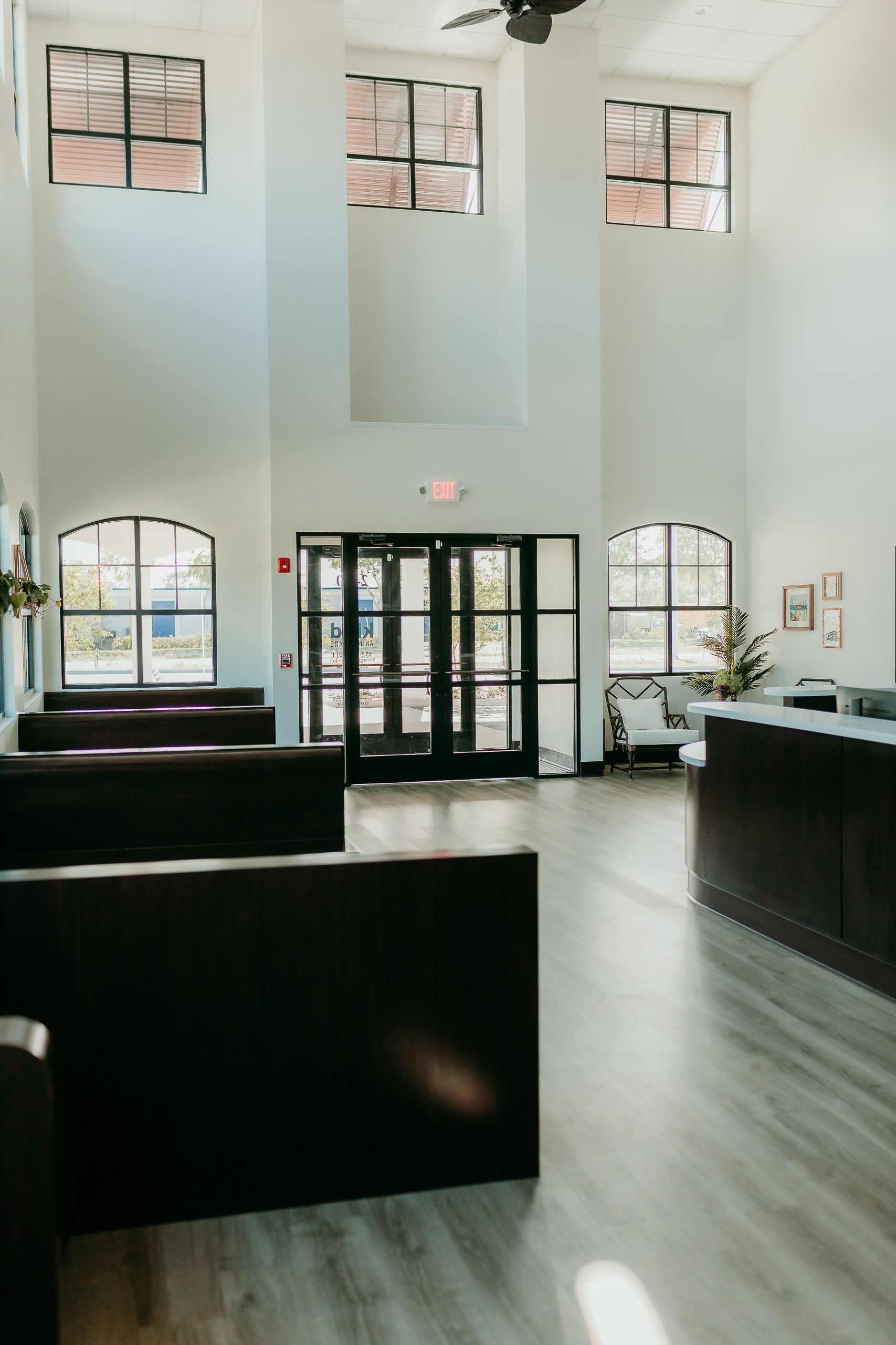 Bright interior with tall windows, black doors, and dark booths; reception desk visible.