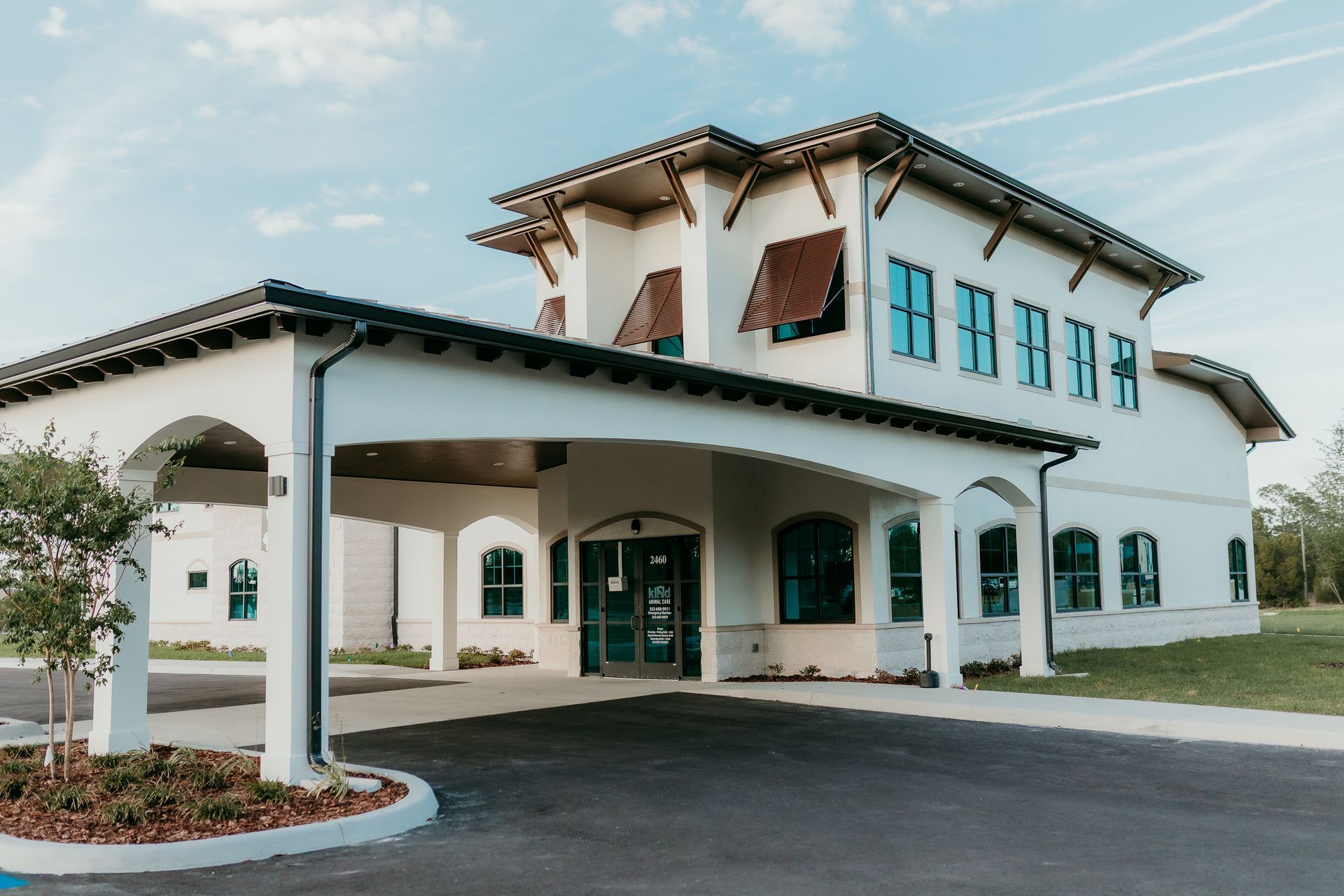 White two-story building with covered entrance and several windows under a blue sky.