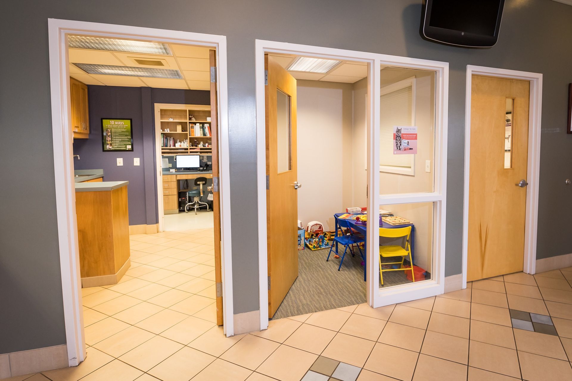 Open doorways lead to various rooms in a clinic setting, including a play area with toys.