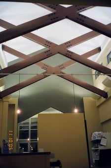 Interior view, yellow walls, exposed wood beams, overhead skylight, two hanging lights.