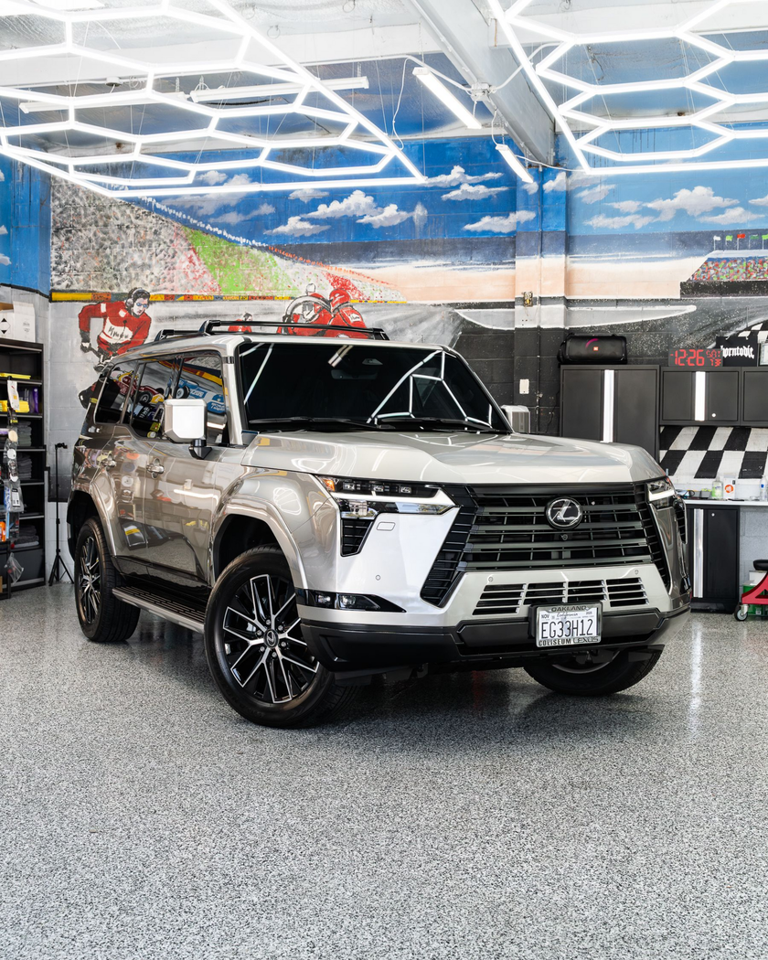 Silver Toyota SUV in a car showroom with blue hexagonal ceiling lights and speckled gray floor