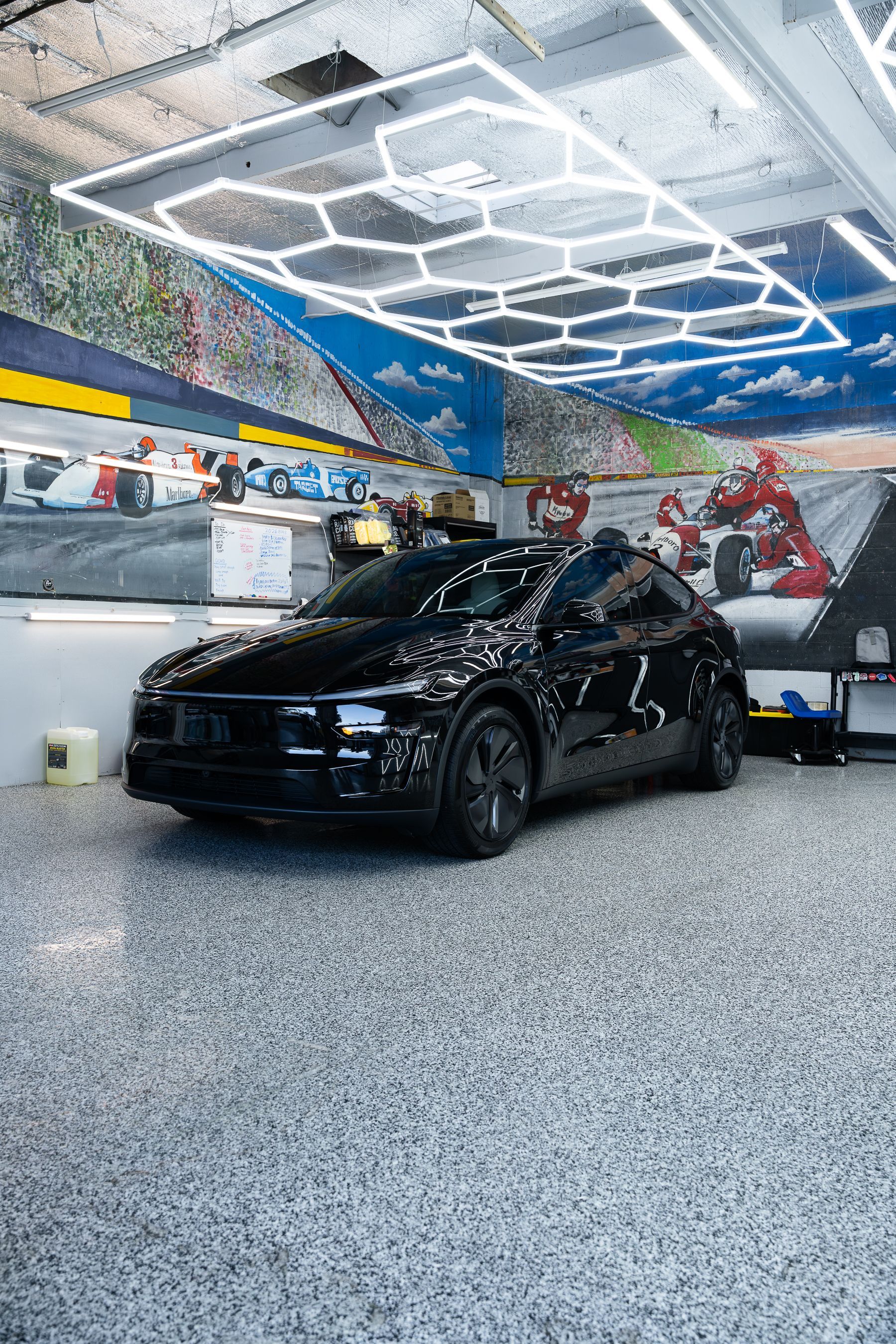 Black SUV in a brightly lit car wash bay with hexagonal ceiling lights