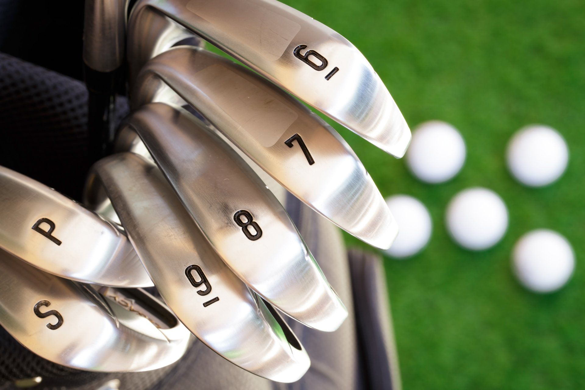 Golf club and blurry golf ball in the green grass.