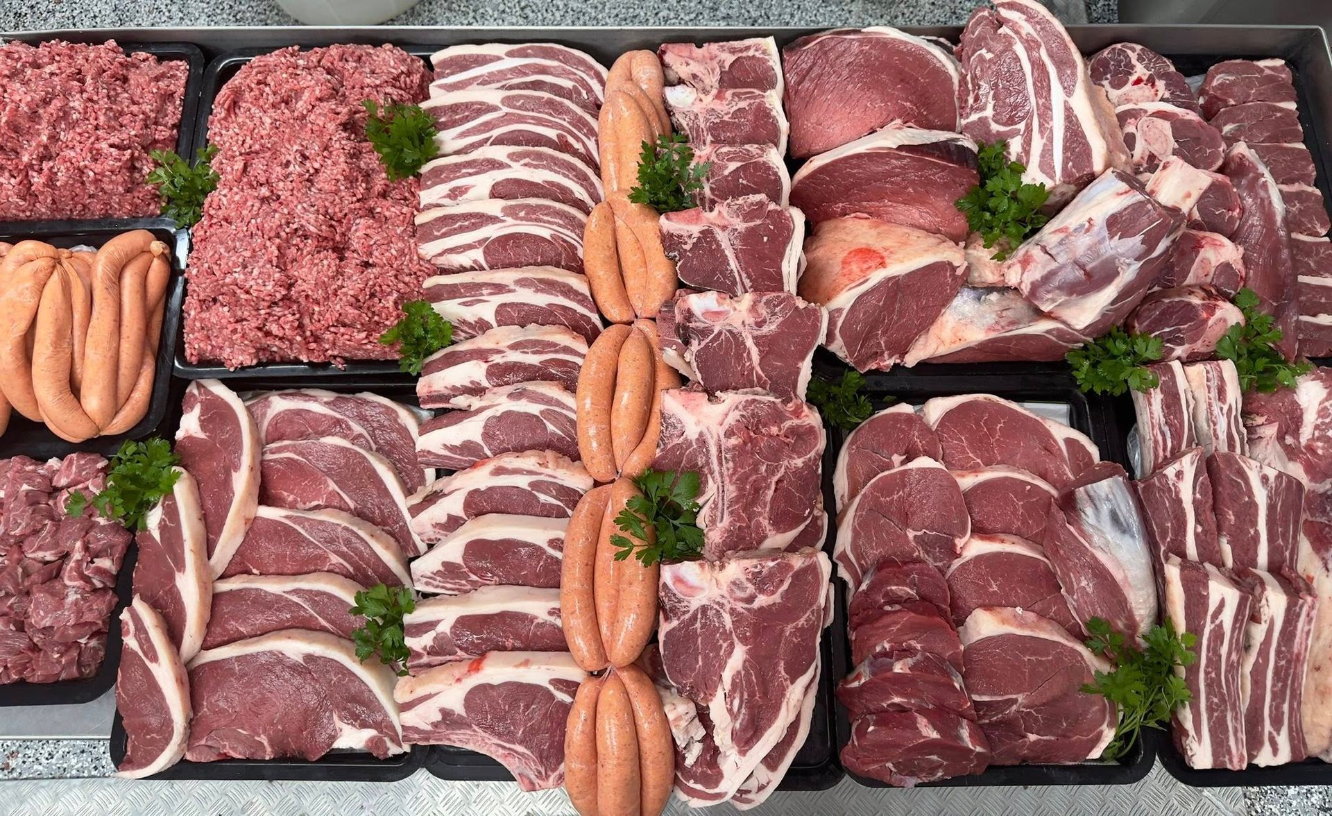 Meat display in a butcher shop with sausages, ground meat, bacon, and various cuts of beef — MBW Wholesale & Bulk In Cannonvale, QLD