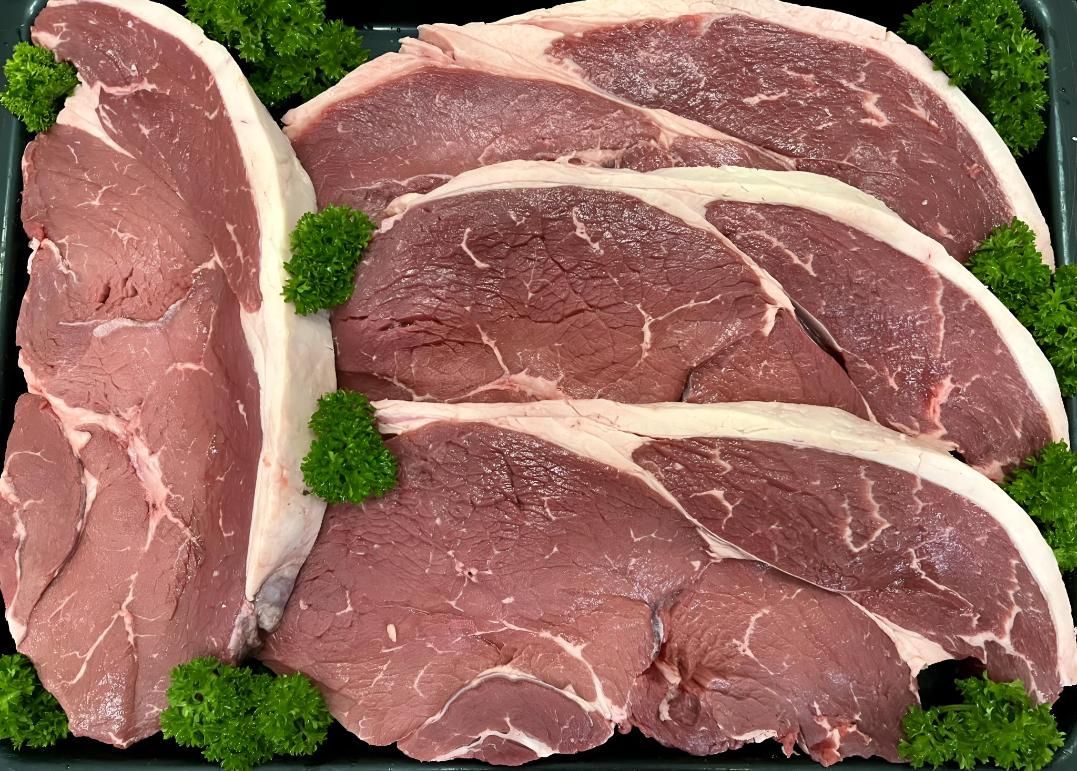 A Tray of Raw Beef Steaks With Parsley on Top — MBW Wholesale & Bulk In Cannonvale, QLD