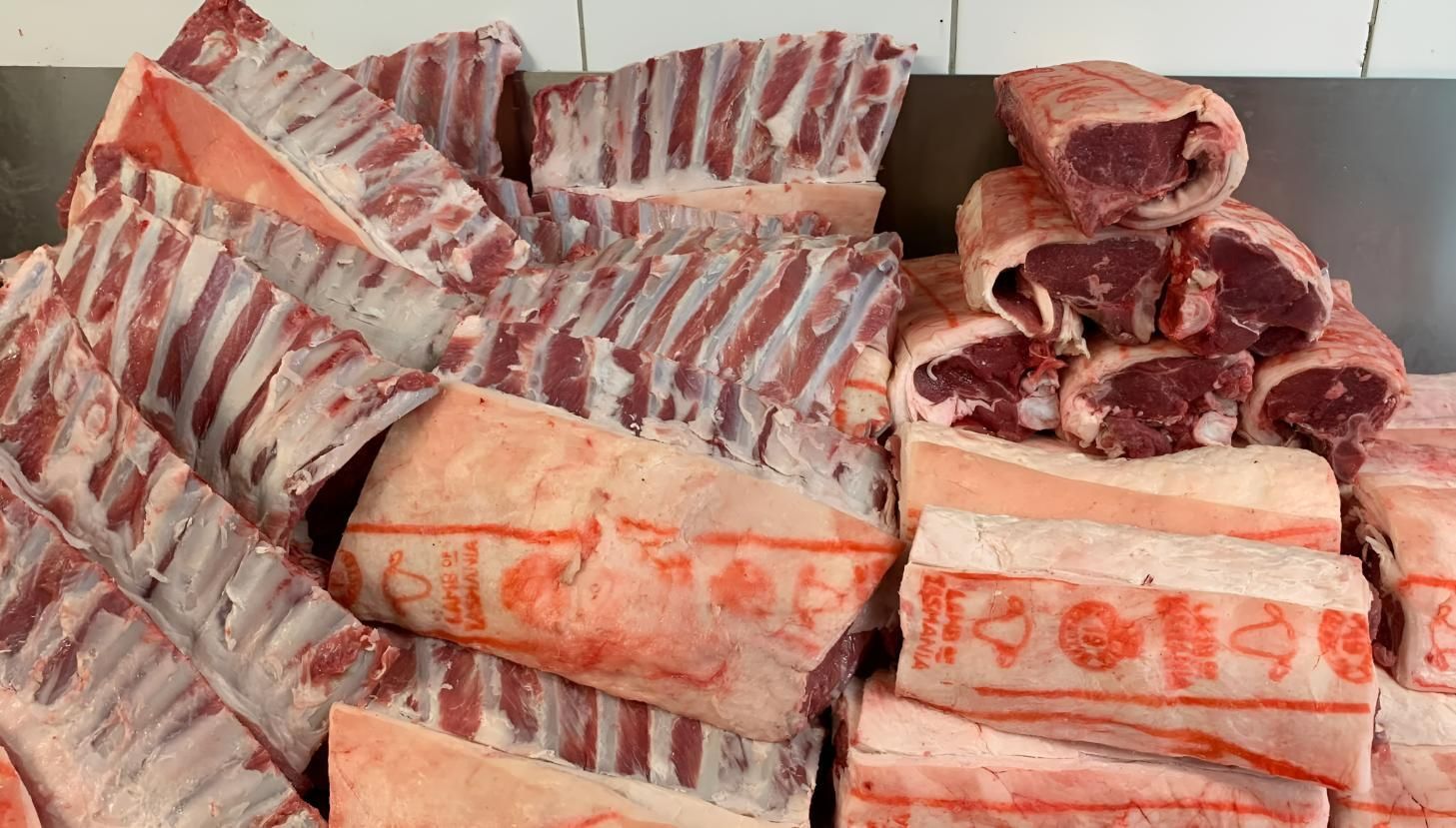 Pile of raw, cut meat with visible ribs and pink flesh, possibly lamb, displayed on a counter.— MBW Wholesale & Bulk In Cannonvale, QLD