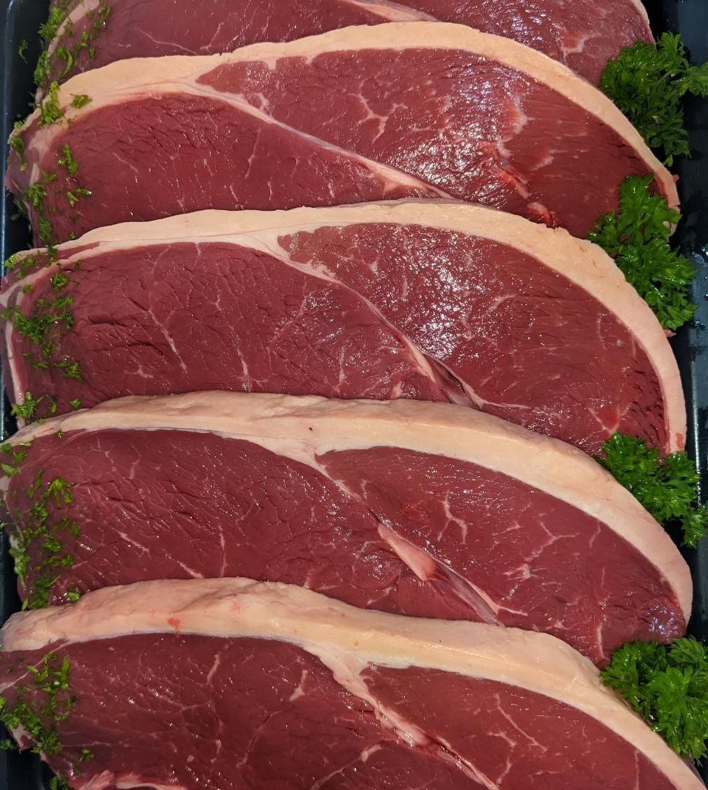 A Tray of Raw Beef Steaks With Parsley on Top — MBW Wholesale & Bulk In Cannonvale, QLD