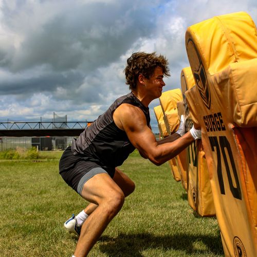 A man is squatting down in front of a blocker with the number 70 on it