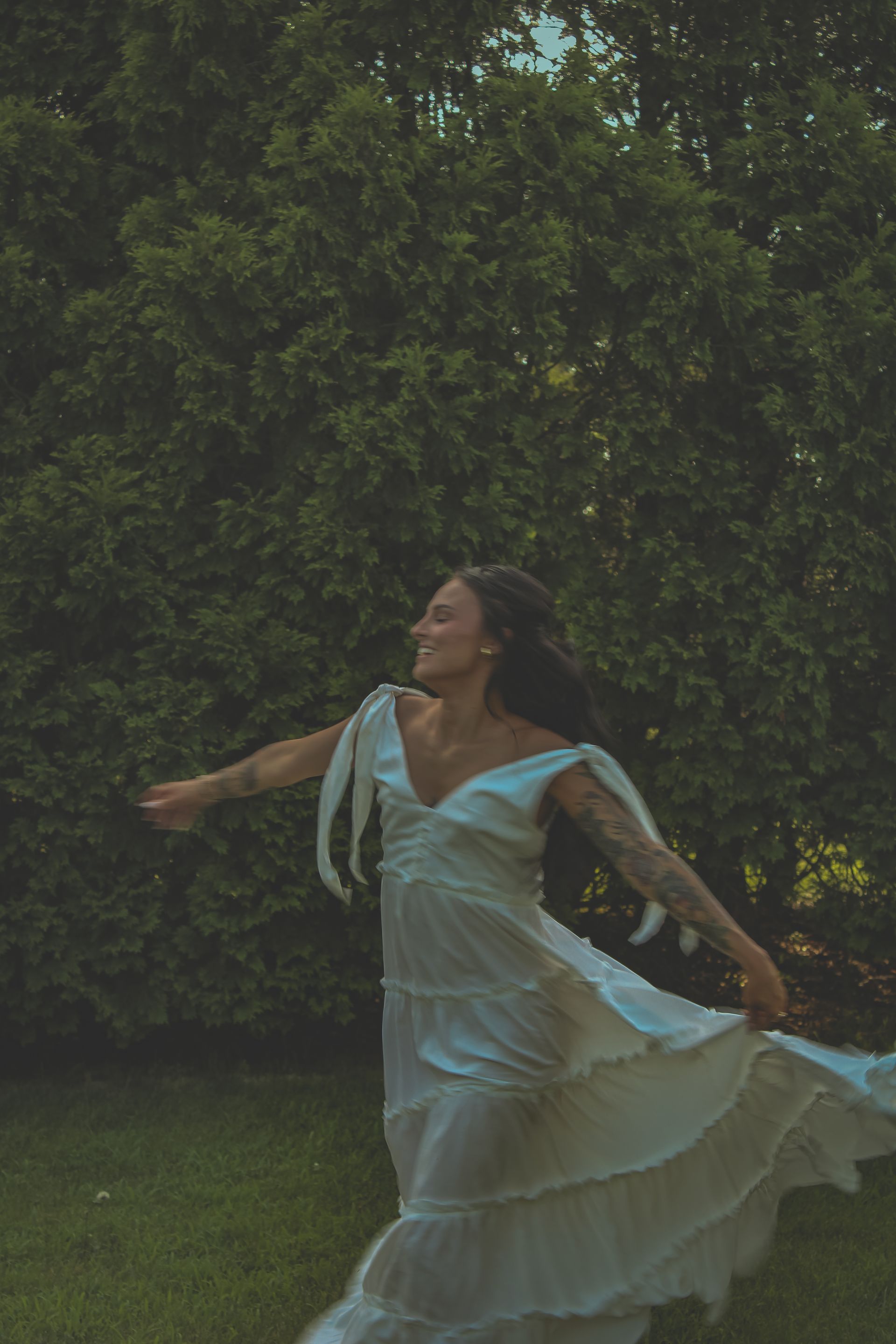 A woman in a white dress is dancing in a field.