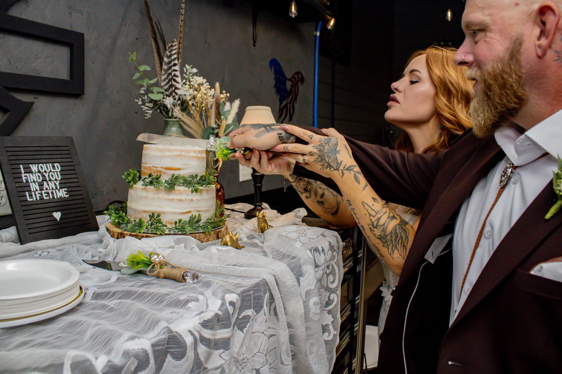 Couple cutting wedding cake at reception, decorated table.