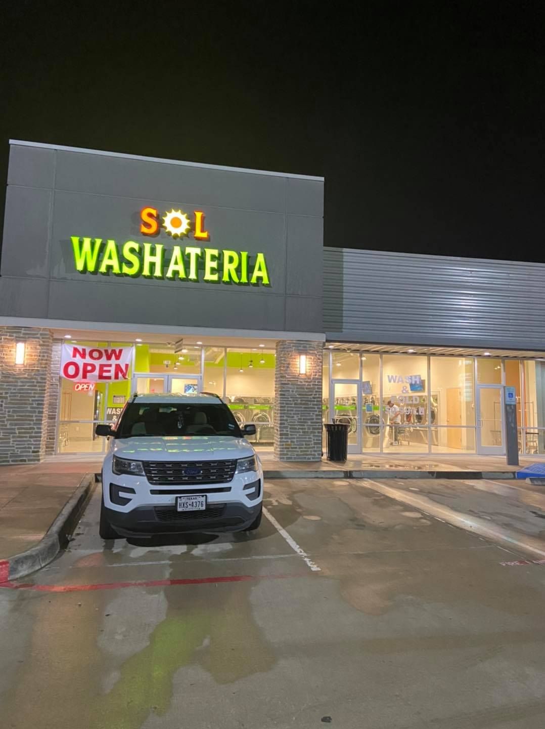 White SUV parked outside a brightly lit 