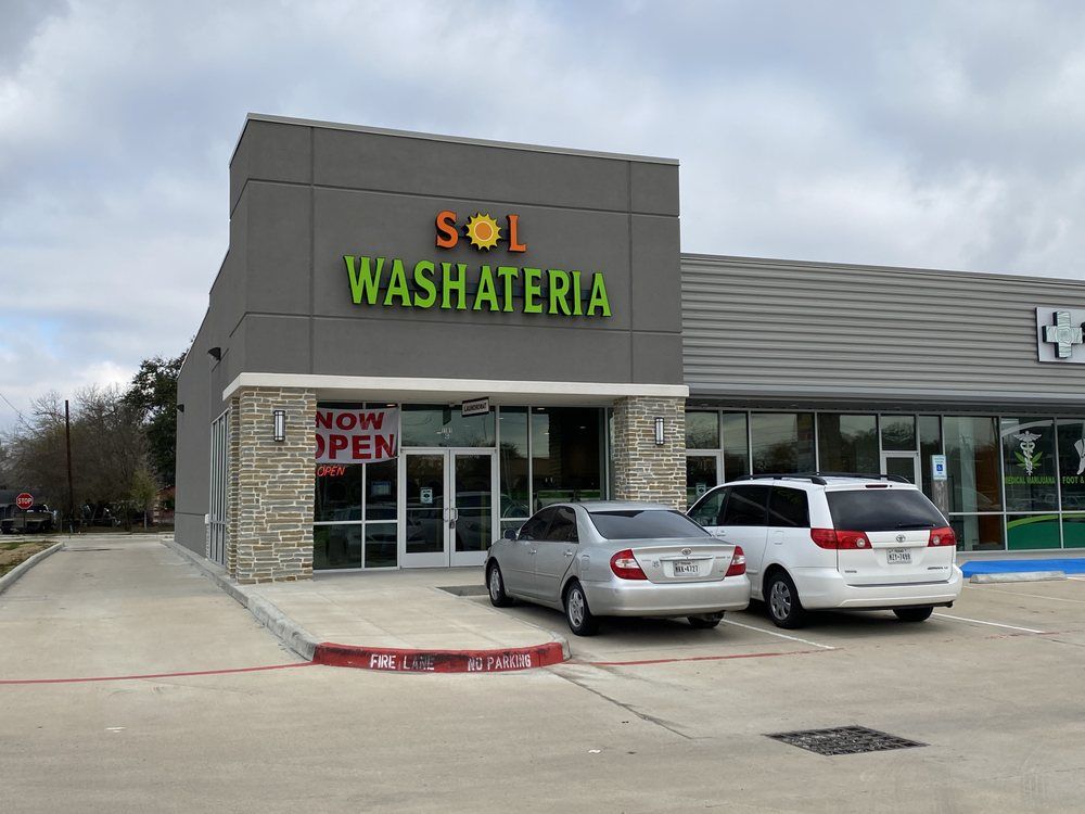 Exterior view of Sol Washateria, a laundromat, with a car and minivan parked in front.