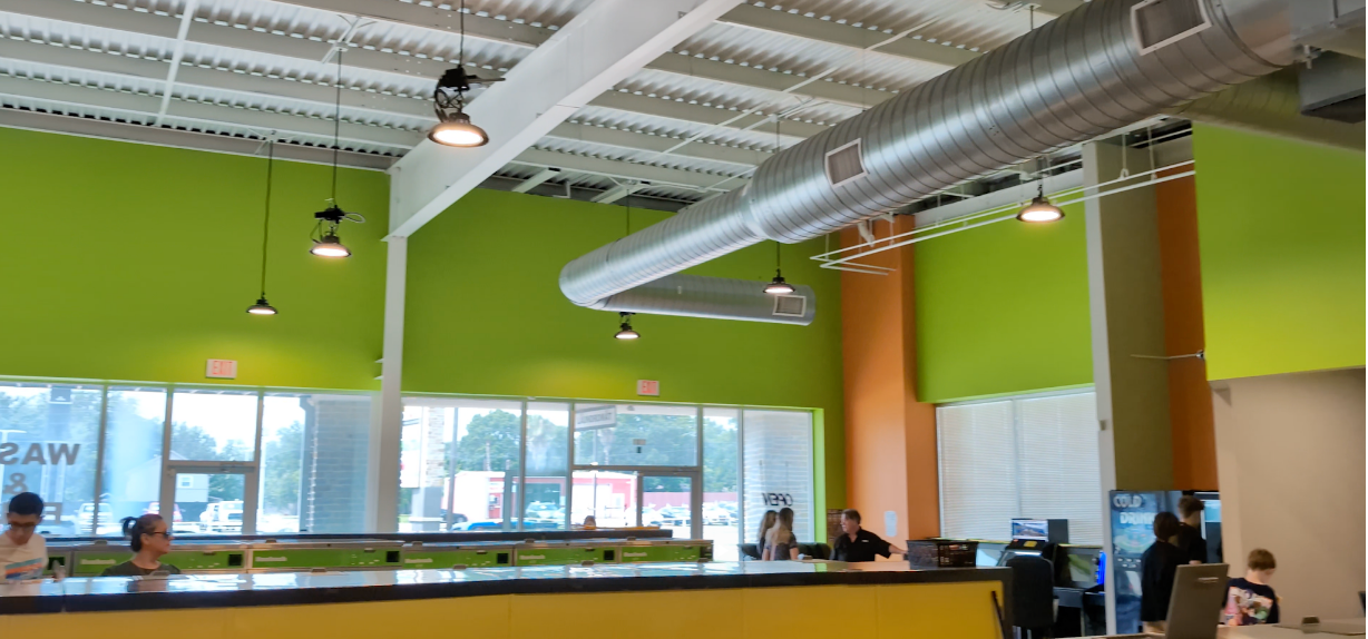 Interior of a brightly colored office with people working. Lime green walls, an orange pillar, and a yellow counter.