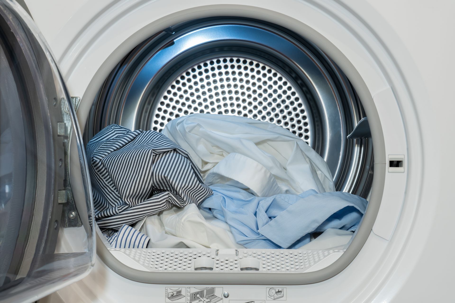 Open dryer with blue and white shirts.