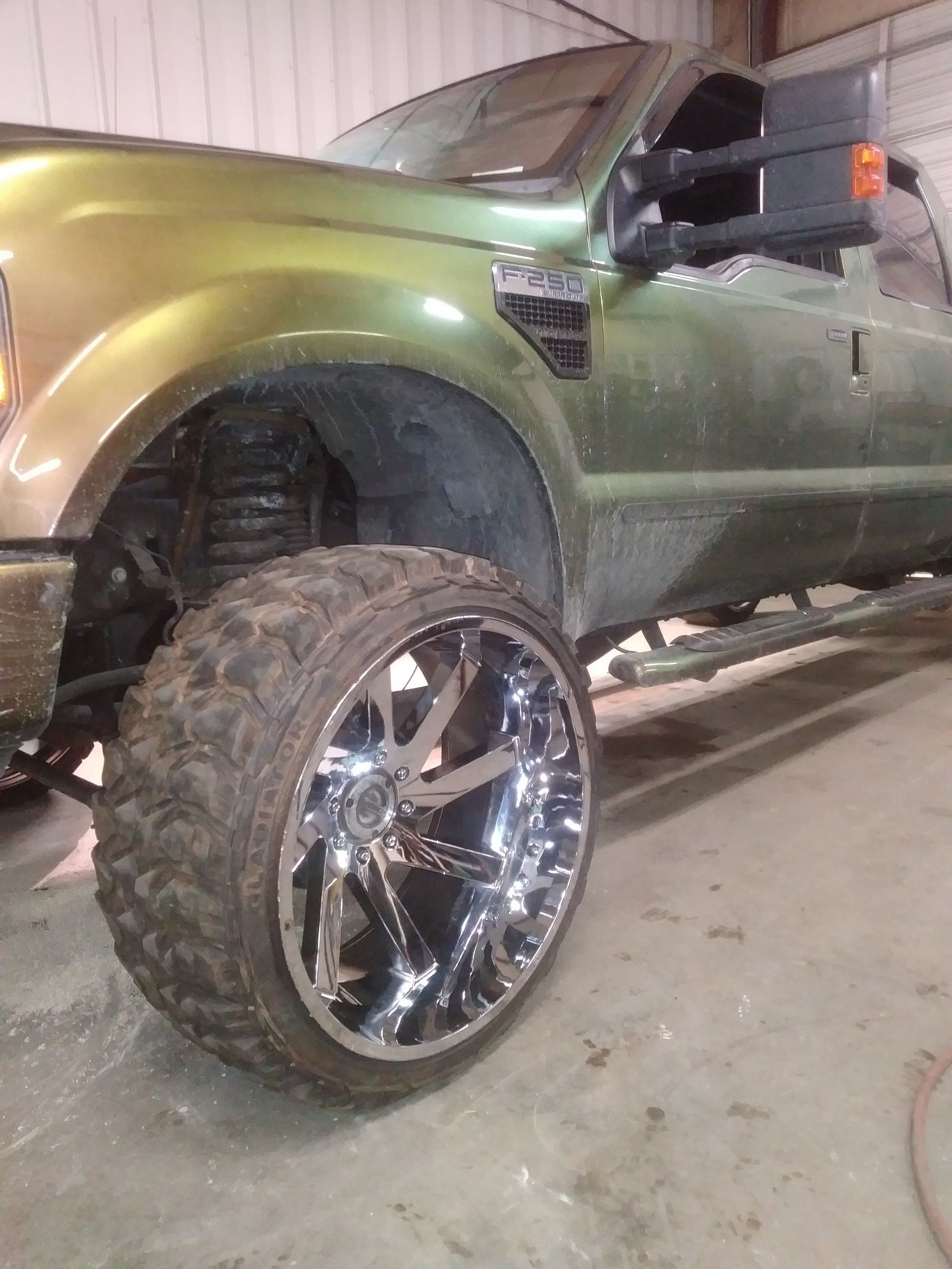 Green truck with chrome wheels, indoors.