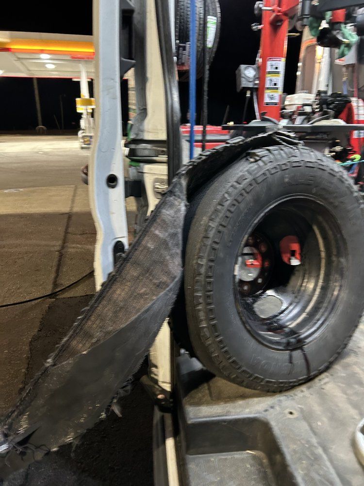 Damaged tire on a white truck at a gas station; the tire is partially detached from the vehicle.