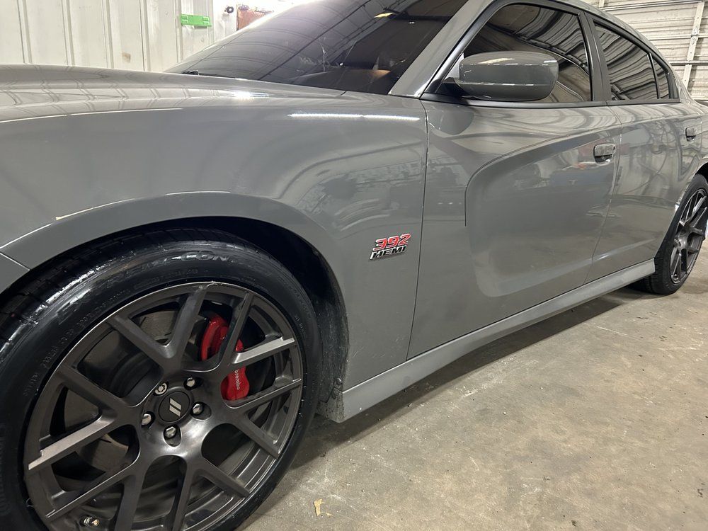 Gray Dodge Charger with red brake calipers, parked inside.