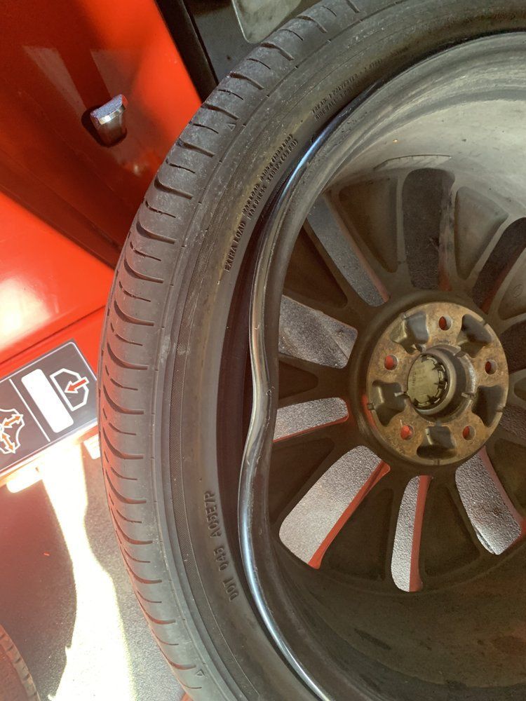 Deformed tire on alloy wheel, likely damaged.