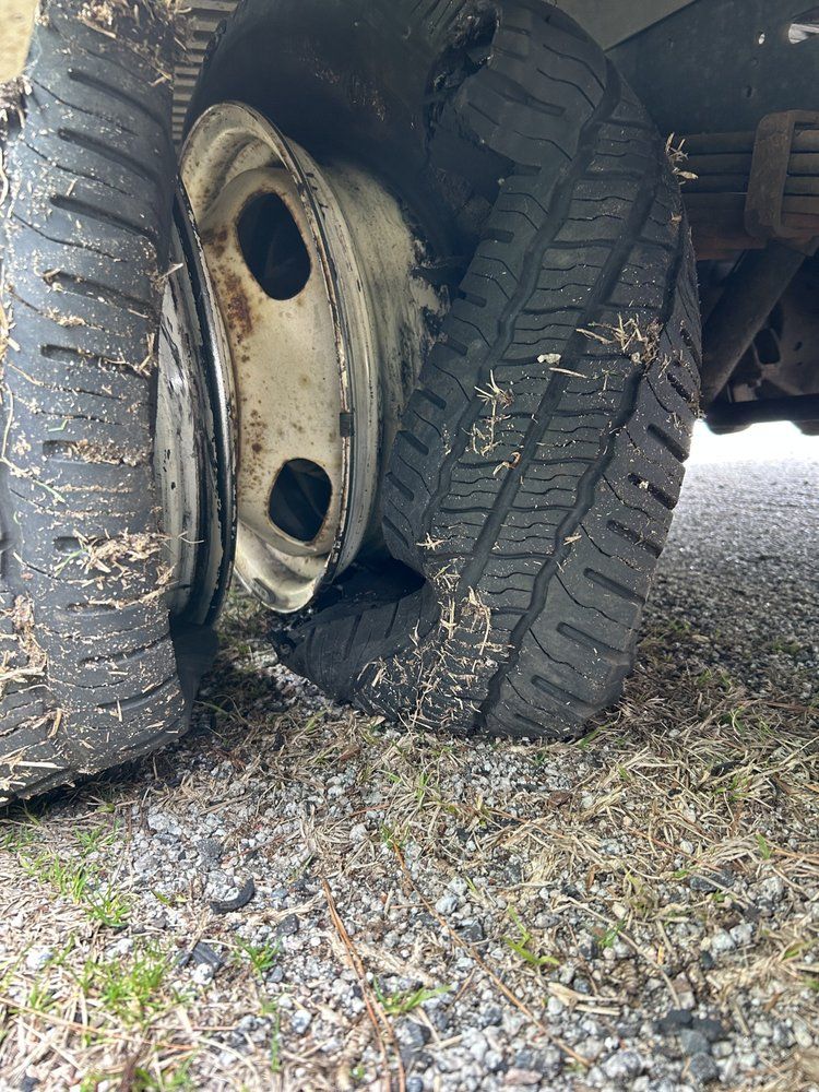 Damaged tires on a vehicle with a flattened tire and dirty wheels.