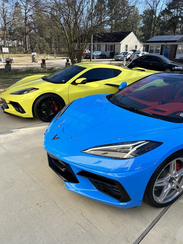 Two Chevrolet Corvette sports cars, one blue, one yellow, parked on pavement.