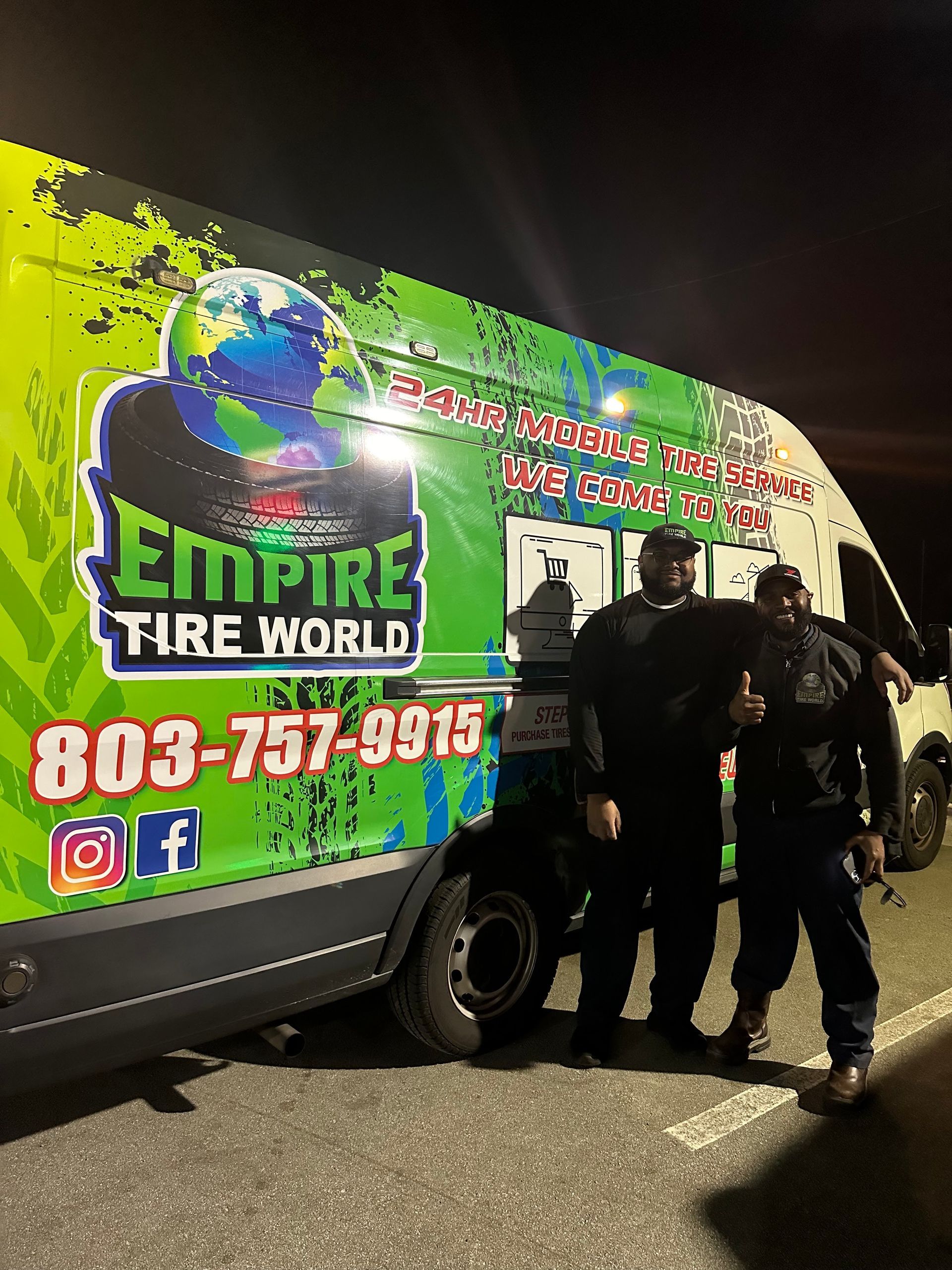 Two men in front of Empire Tire World van; green, black, and blue graphics, outdoors at night.