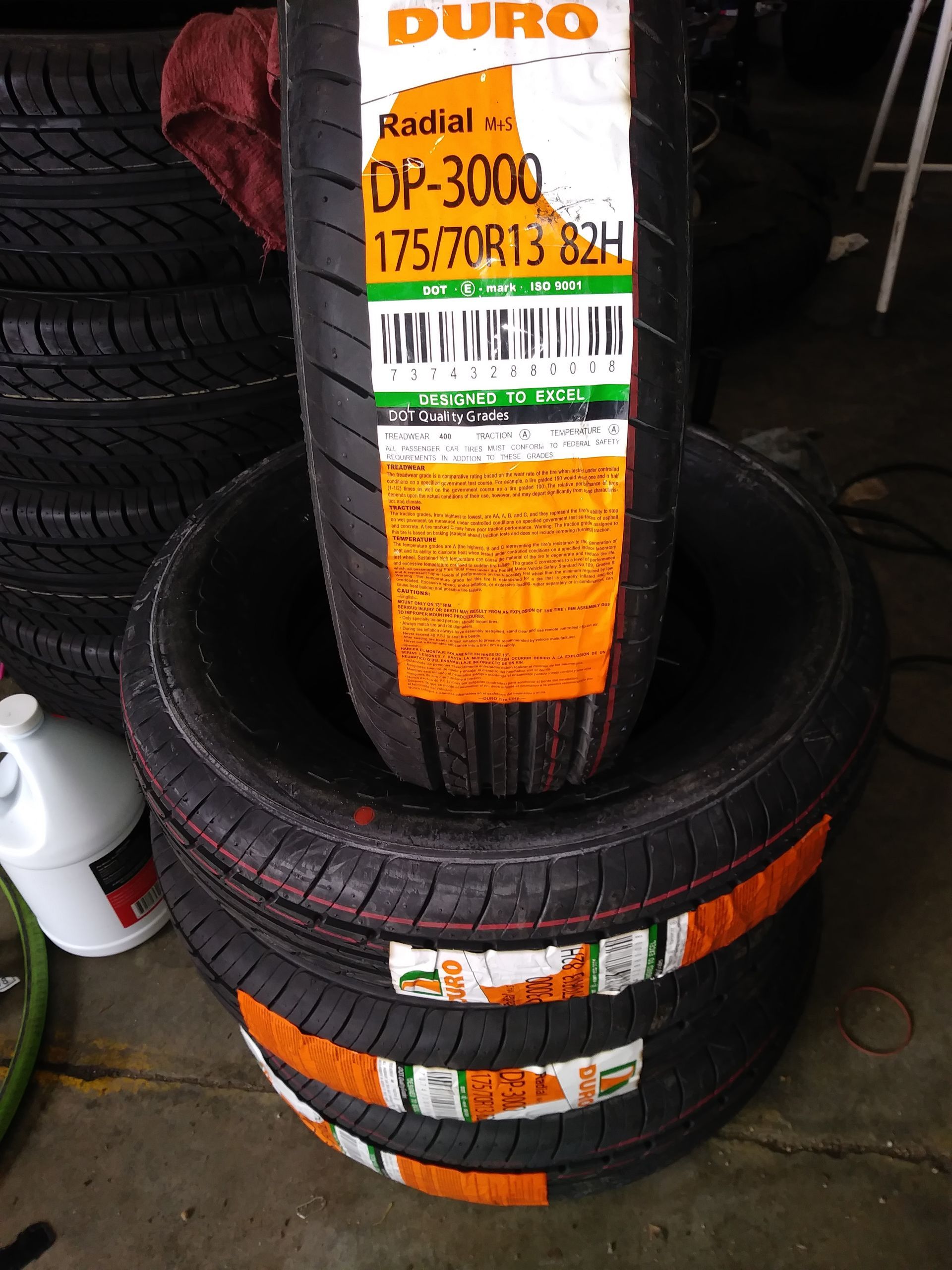 Tires stacked, showing a Duro DP-3000 175/70R13 82H tire with label.