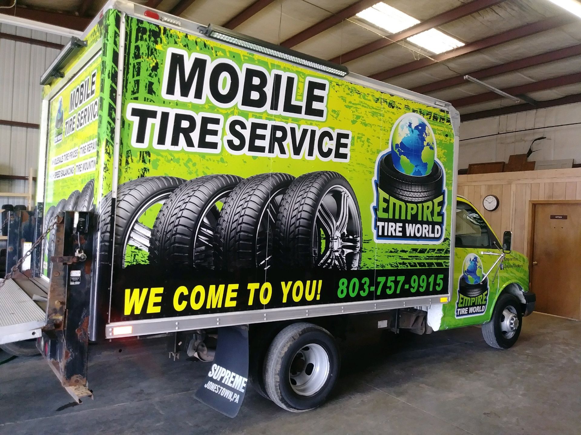 Mobile tire service truck with green and black graphics, showing tires and phone number, “We come to you!”.