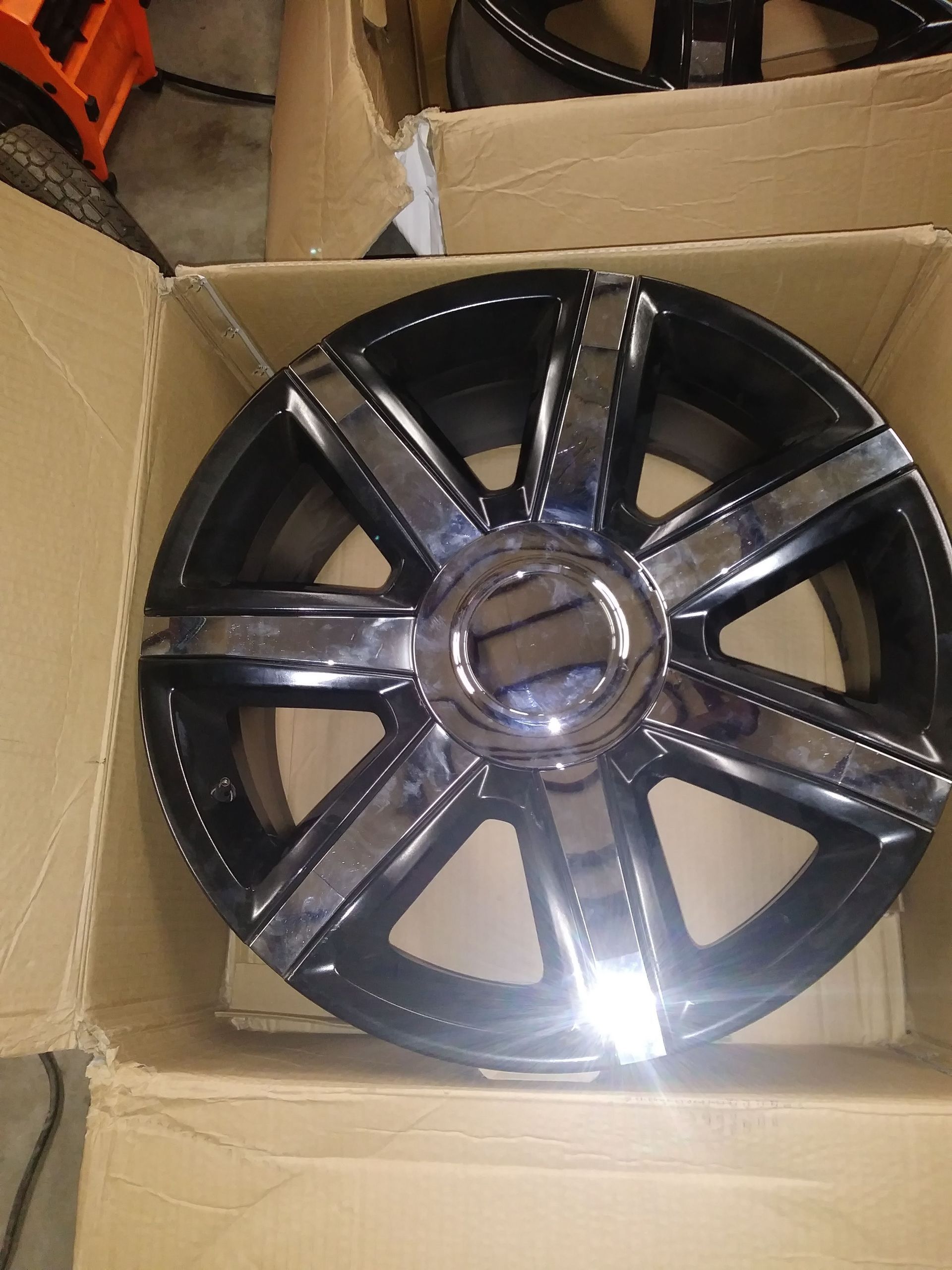 Black and chrome car rim in cardboard box.