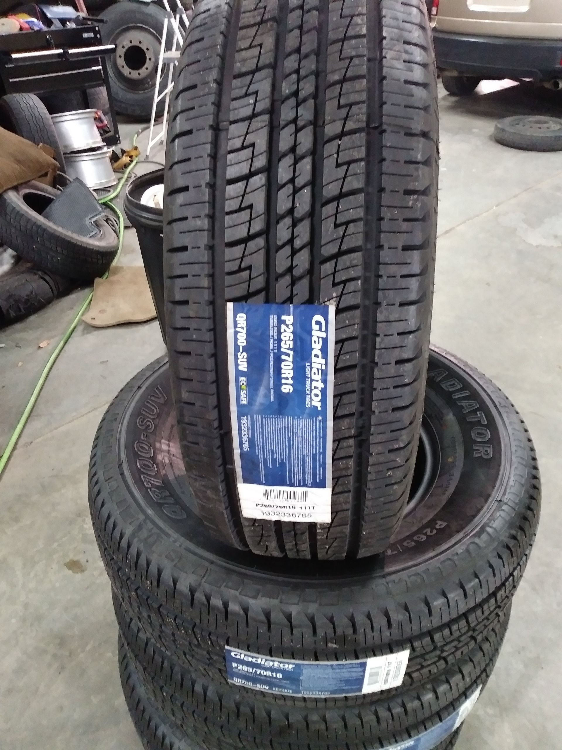 Stack of new black Gladiator tires with a label, indoors.