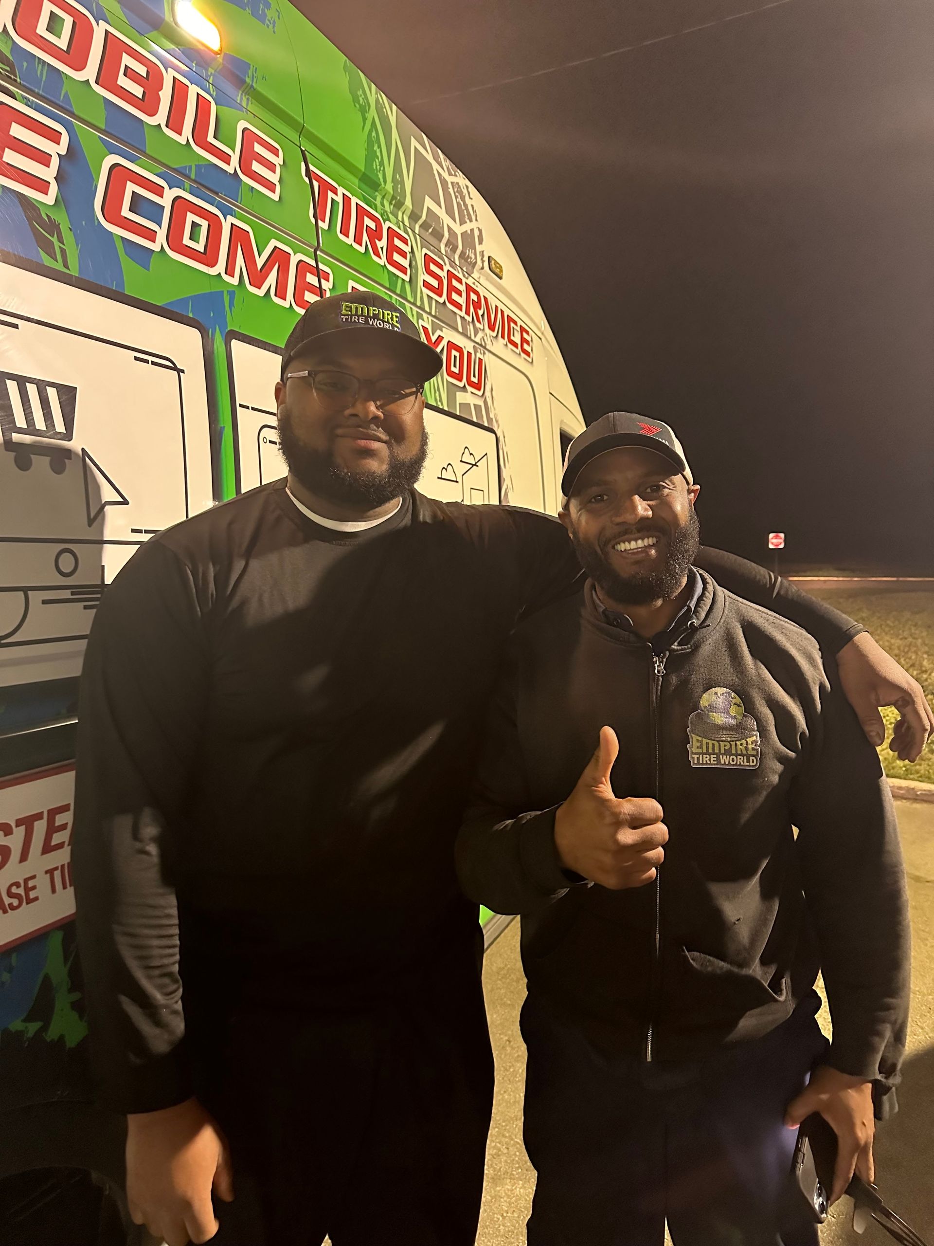 Two men pose by a mobile tire service truck. One gives a thumbs-up.