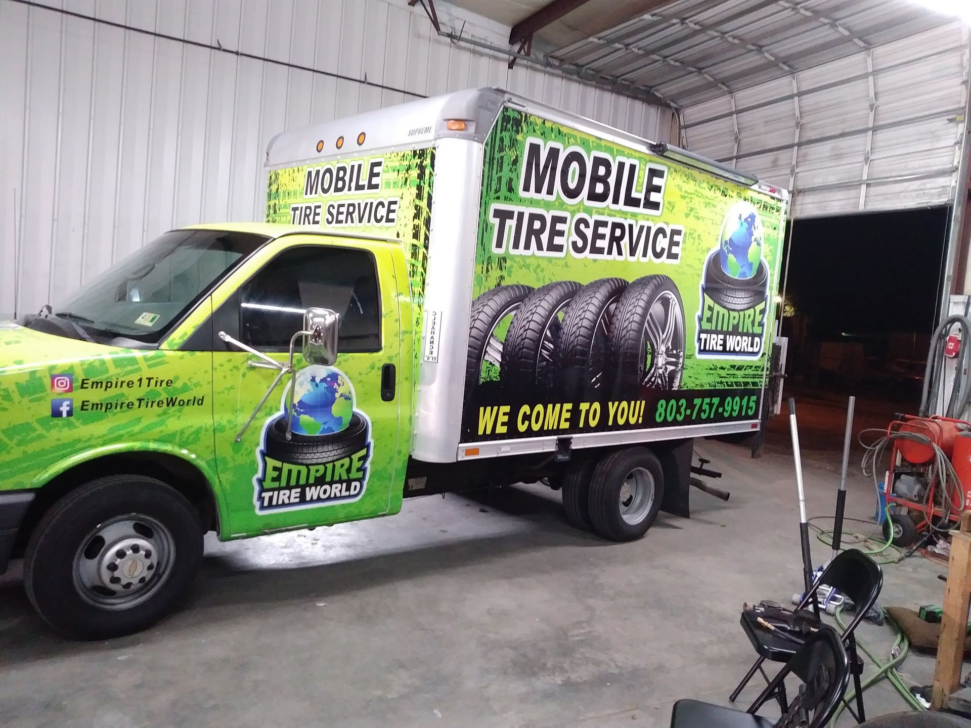 Mobile tire service truck with green and black graphics, parked in a garage.