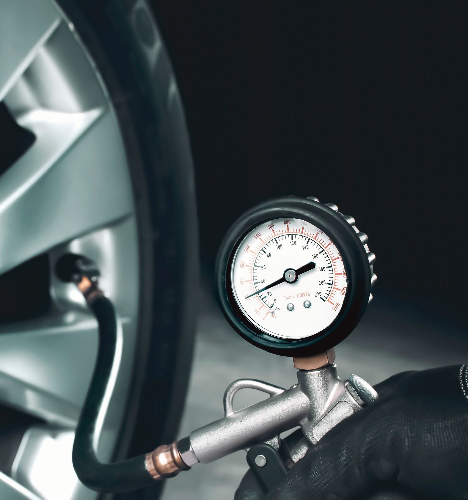Tire pressure gauge connected to a car tire, showing the air pressure.