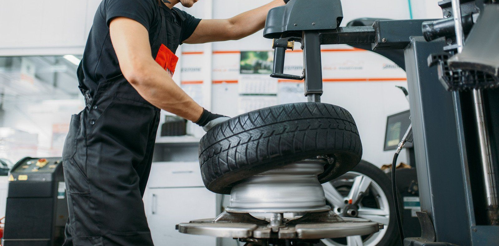 Mechanic using a tire machine to remove a tire in a garage.