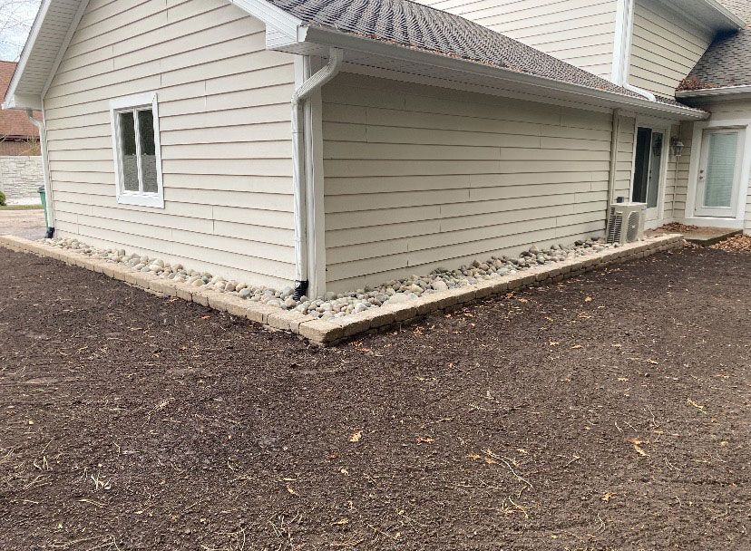 A white house with a gravel driveway in front of it.