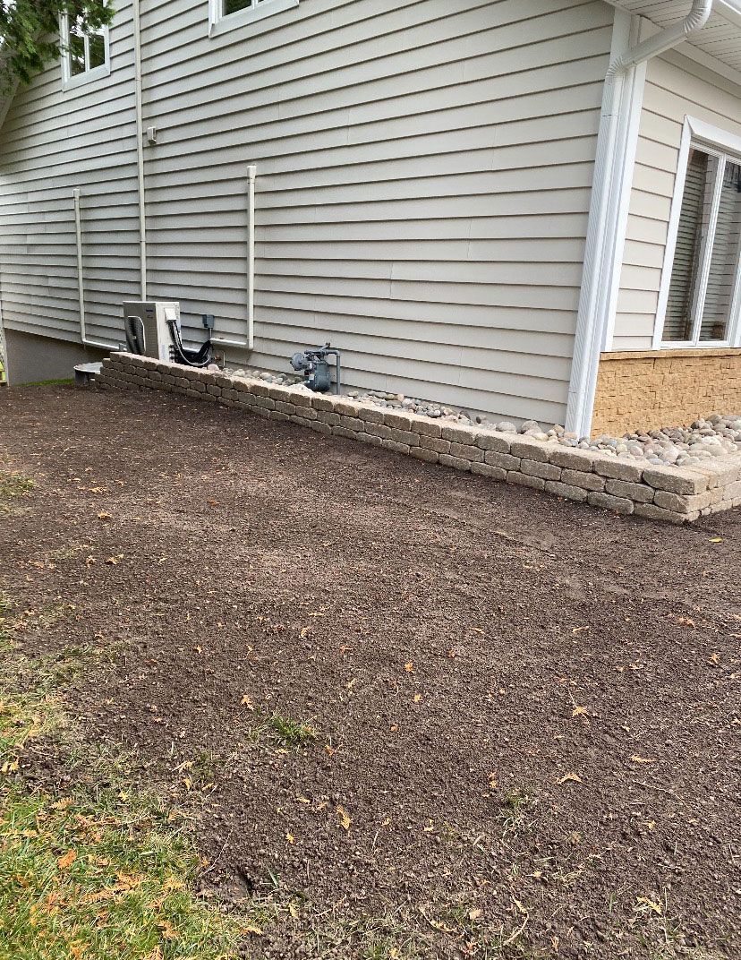 A house with a brick wall and a patio in front of it.