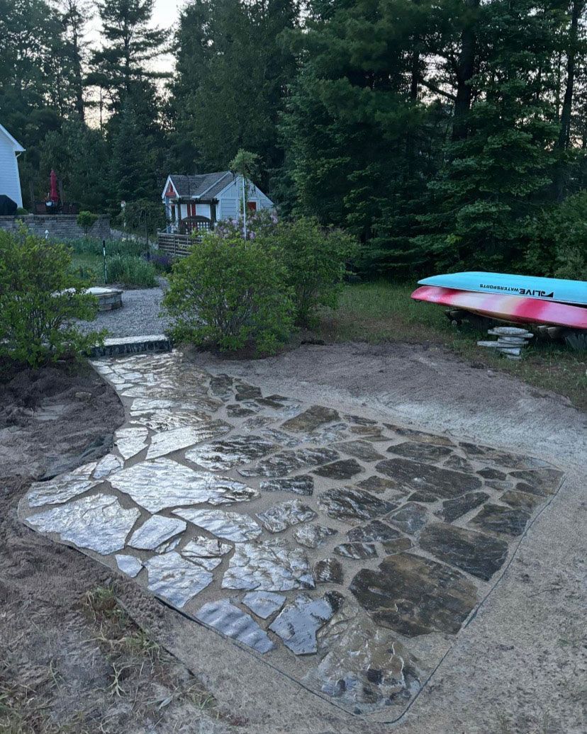 A stone walkway leading to a house in the woods.