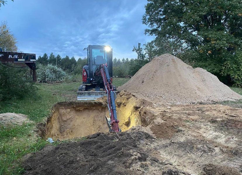 A bulldozer is digging a hole in the ground next to a pile of dirt.