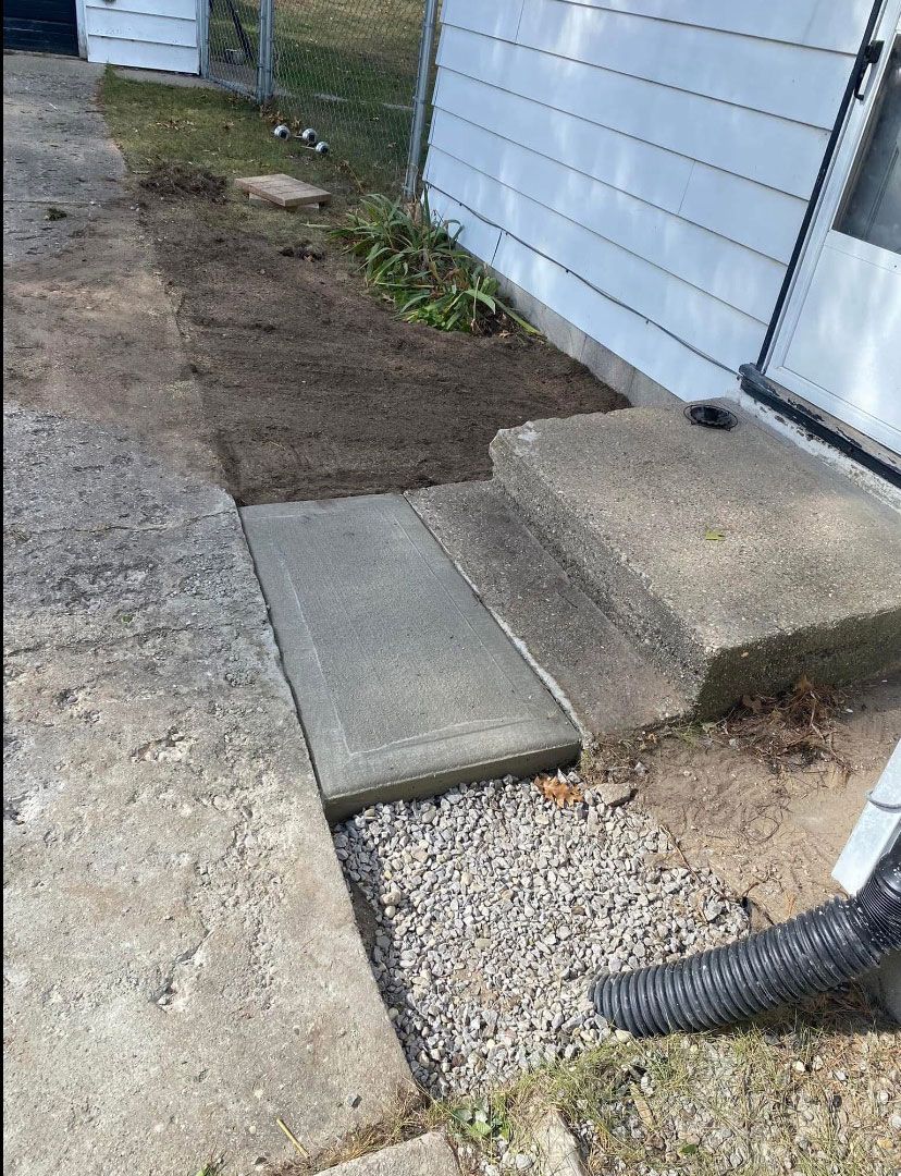 A vacuum cleaner is being used to clean a sidewalk next to a house.
