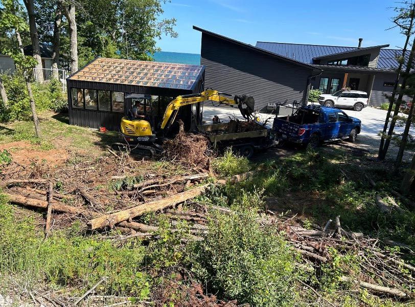 A yellow excavator is moving dirt in front of a house.