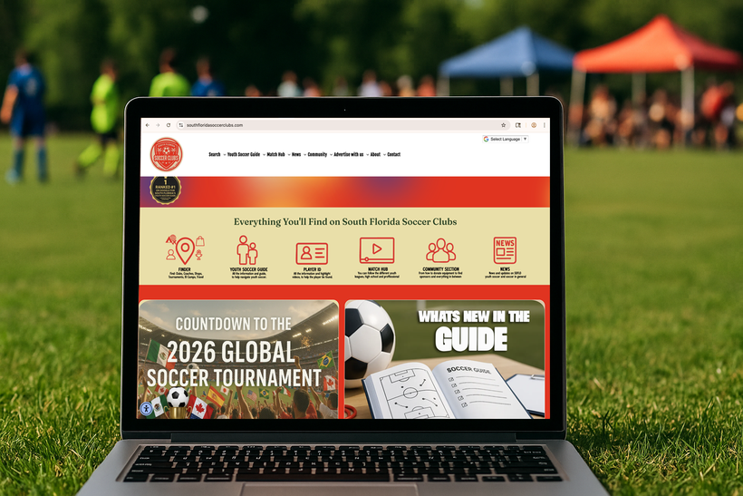 Laptop displaying a soccer website, set on a grassy field with a blurred soccer game in the background. The website announces the 2026 Global Soccer Tournament.