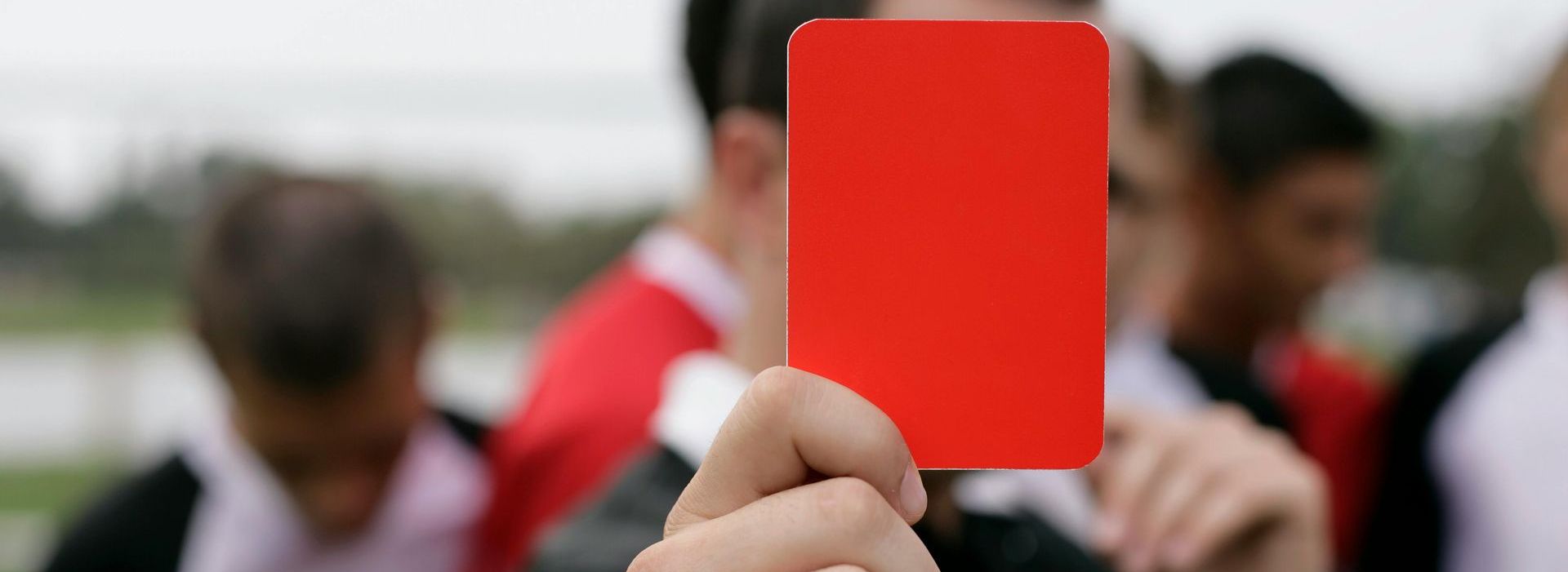 A person is holding a red card in front of their face