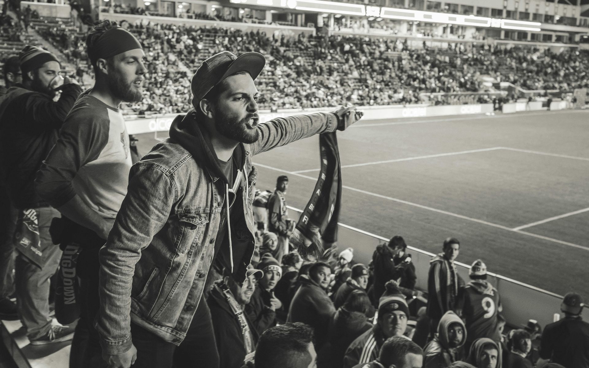 A man is standing in front of a crowd of people at a soccer game.