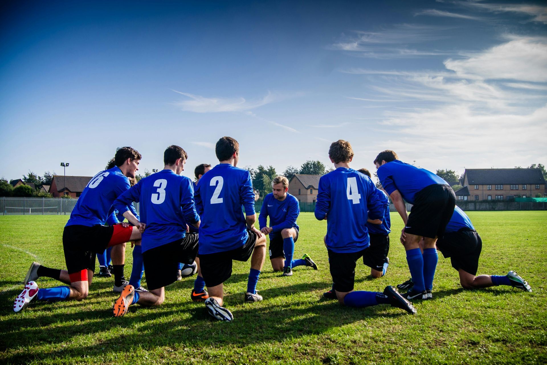 A group of soccer players are sitting in a huddle on a field.