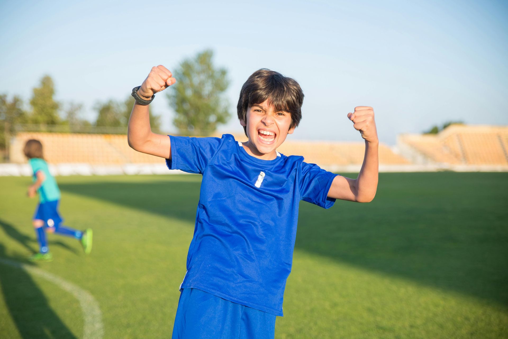 A young boy is flexing his muscles on a soccer field.