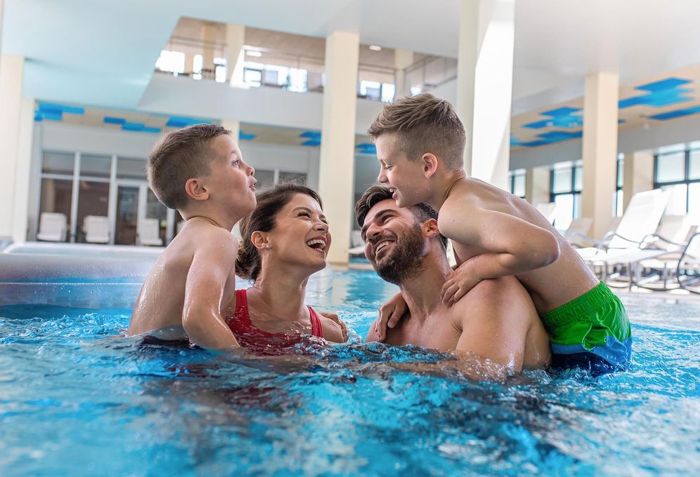 a family is playing in a swimming pool .