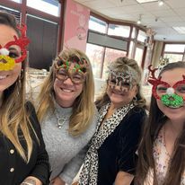 A group of women wearing christmas masks are posing for a picture.