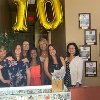 A group of women are posing for a picture in front of a 10 balloon.