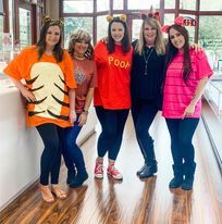 A group of women dressed in winnie the pooh costumes are posing for a picture.