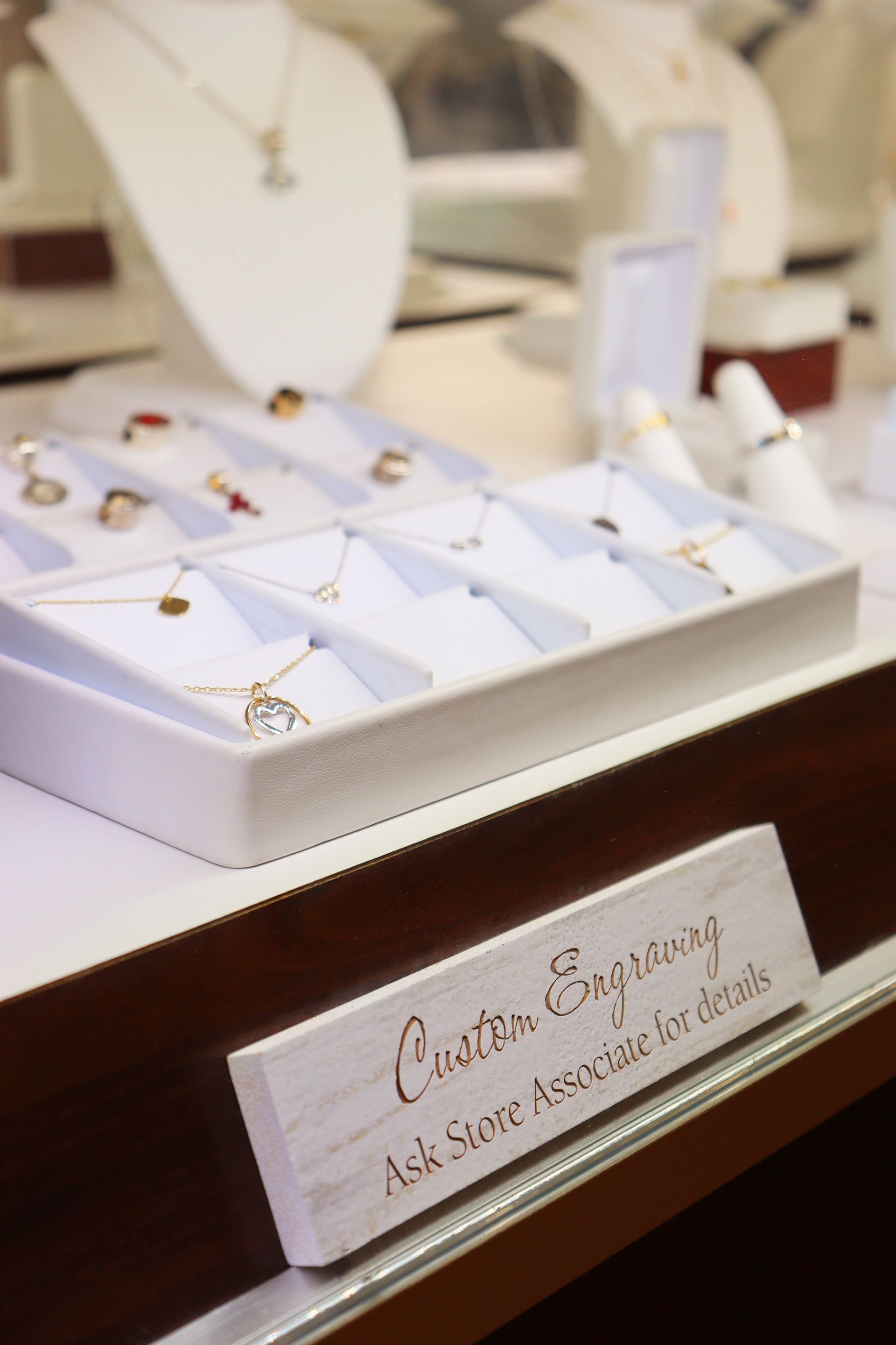 A display of jewelry including necklaces and rings with a sign that says