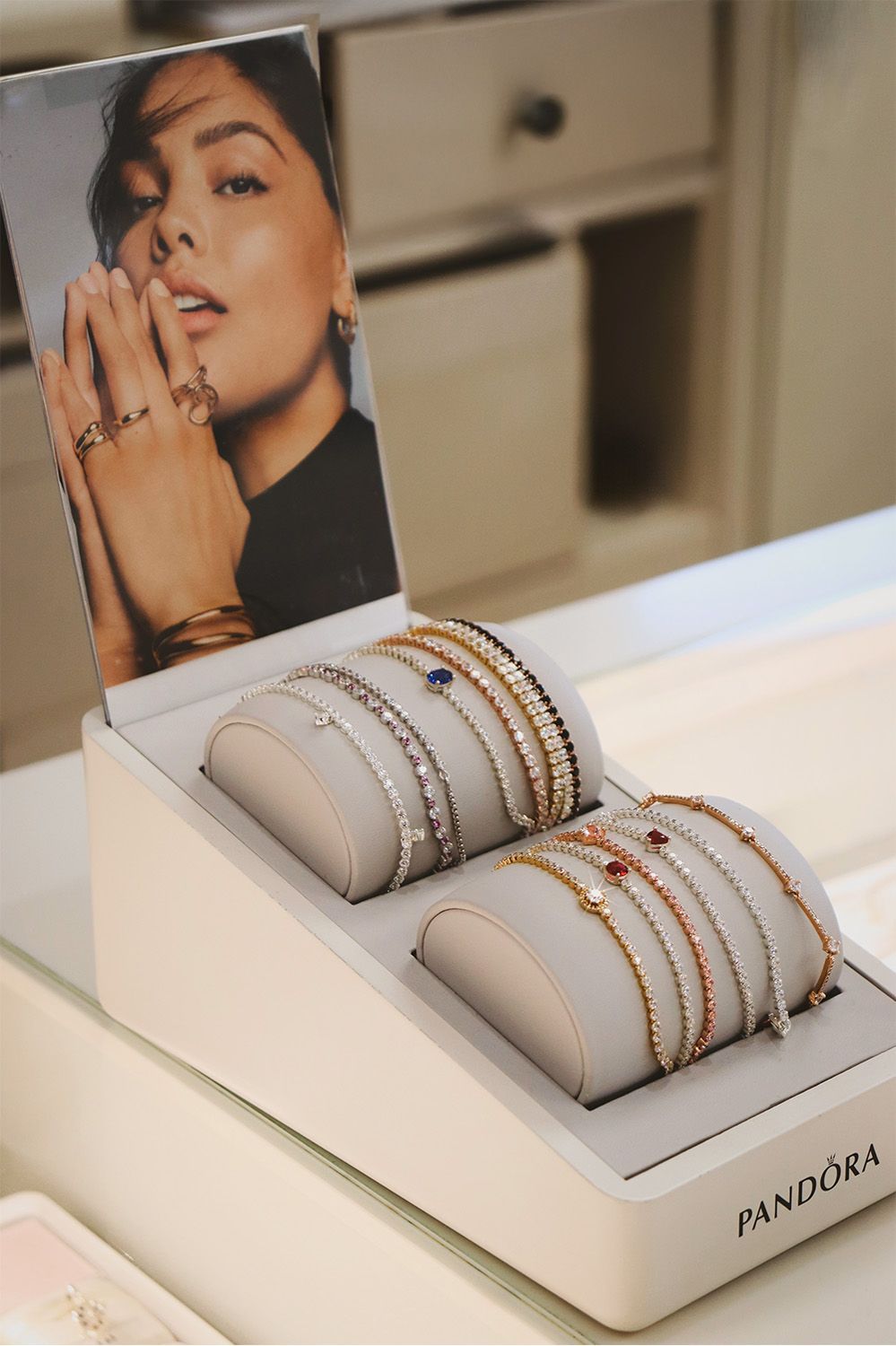 A display case filled with bracelets and a picture of a woman.